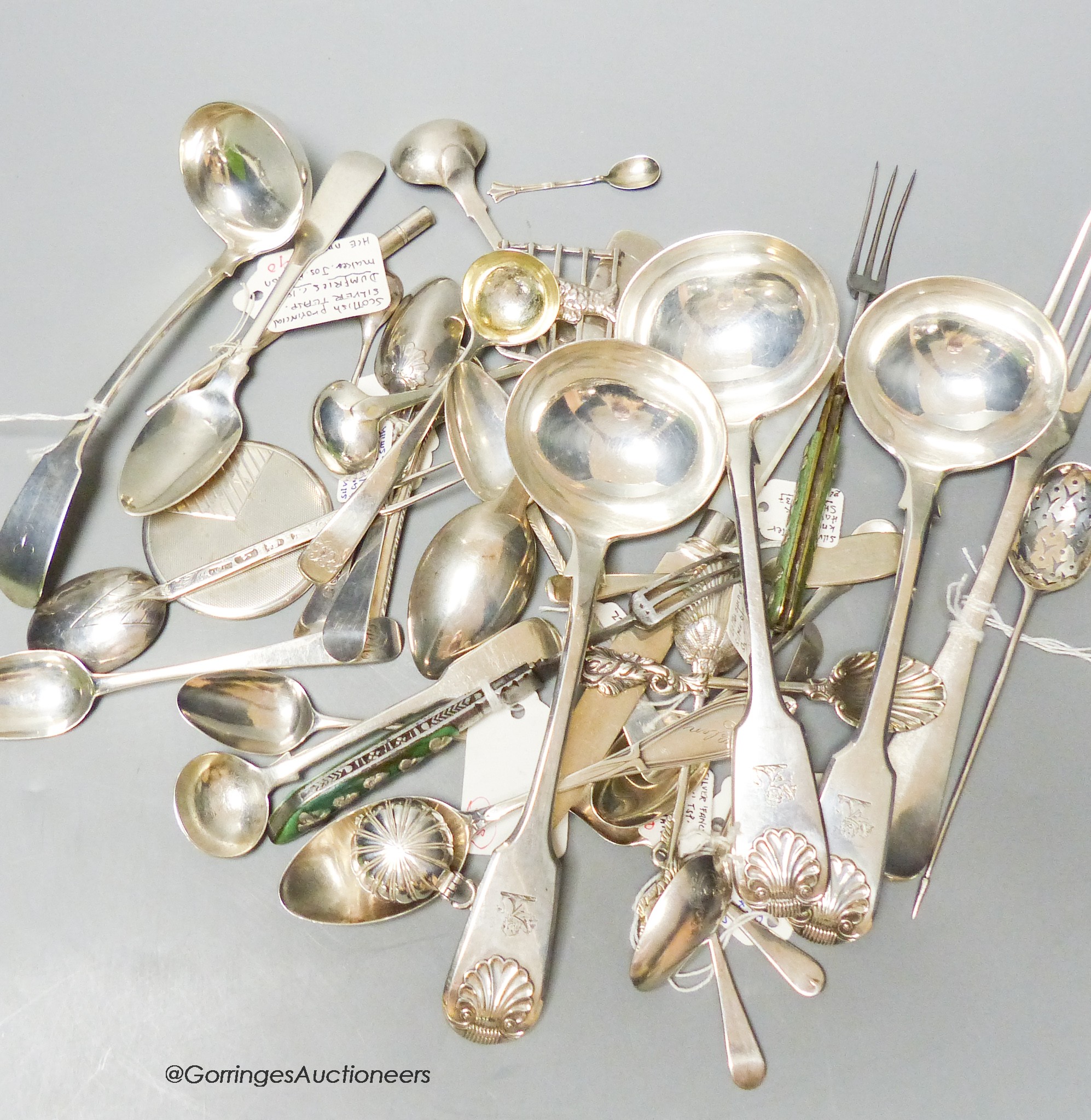 A mixed collection of silver and white metal spoons and other flatware including three 19th century fiddle and shell pattern sauce ladles, a Georgian mote spoon, a Dumfries teaspoon by Joseph Pearson, a Jersey teaspoon b